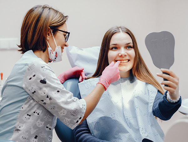 Dental professional showing female patient mirror of smile in modern clinic office.