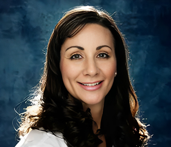 Professional headshot of woman with long dark hair smiling against blue background